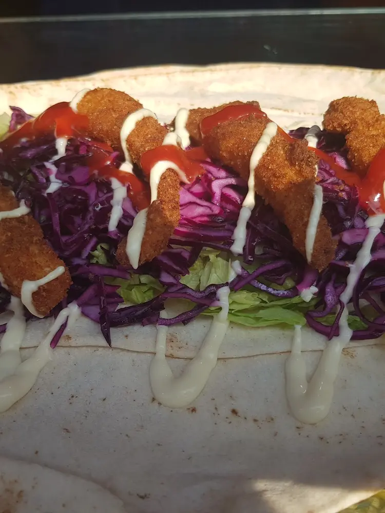 Open flatbread wrap laid with chicken goujons, red cabbage, lettuce and sauces